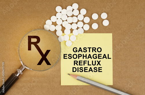 On the table are pills, a magnifying glass, pencils and a sticker with the inscription Gastro Esophageal Reflux Disease