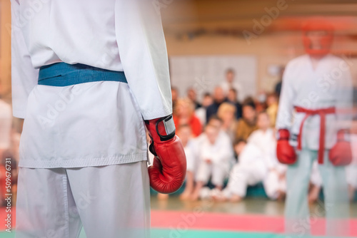 Karate athlete in red gloves on the mat before the fight. Martial arts background with motion blur.
