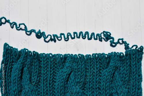 Dissolve hand knitted knitwear made of thick yarn with a braid pattern. edge of knitting with open loops and wavy thread on light background. untangling related things