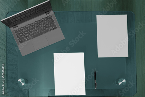 .Table with laptop and blank sheets of paper with space for writing