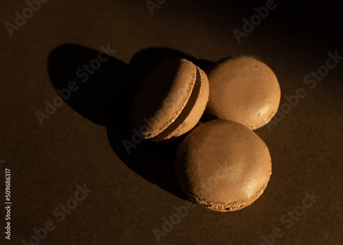 Home made chocolate macaroon french pastry.Three chocolate macaron on a brown background.French meringue cookies macaron