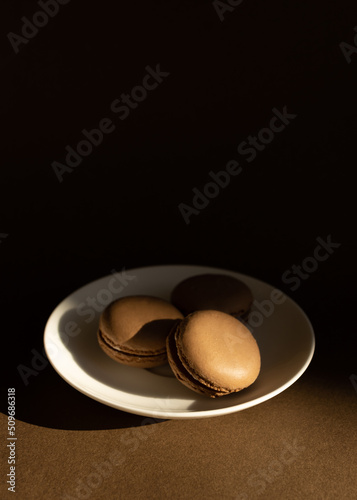 Home made chocolate macaroon french pastry.Three chocolate macaron on a brown background.French meringue cookies macaron