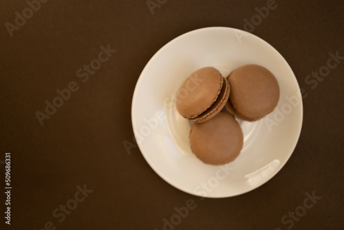 Home made chocolate macaroon french pastry.Three chocolate macaron on a brown background.French meringue cookies macaron