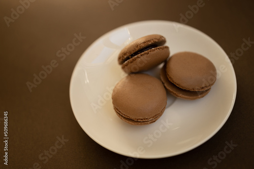 Home made chocolate macaroon french pastry.Three chocolate macaron on a brown background.French meringue cookies macaron