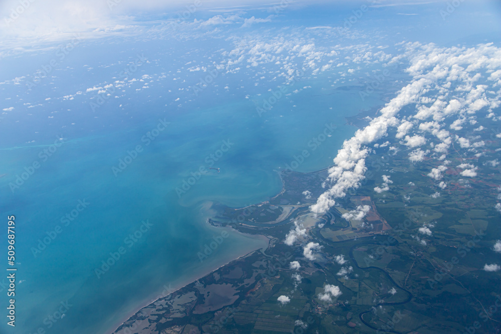 Aerial view of blue ocean and coast land with a few clouds