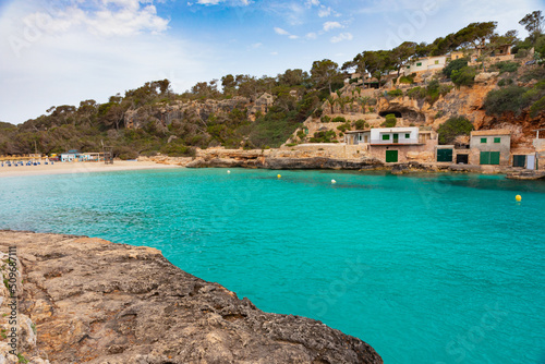 Playa de Cala Llombards, una pequeña cala en Mallorca, de aguas transparentes de color turquesa, con casas de pescadores y 