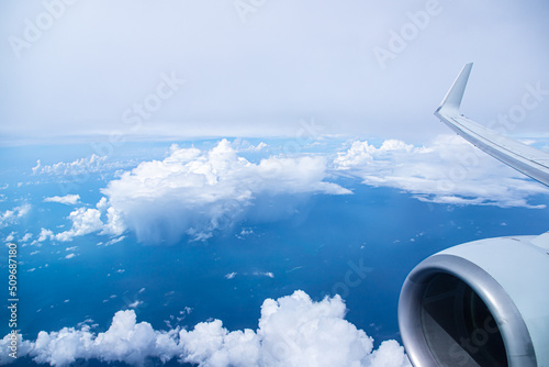Aerial view of blue ocean with a few clouds  an airplane wing and turbine 