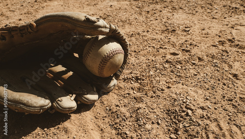 Photography Old used baseball glove and ball on dirt of sports field closeup, copy space on background