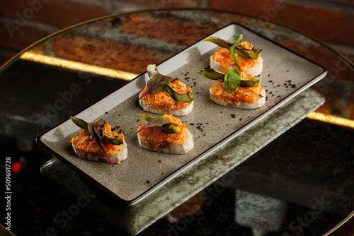 Obraz na płótnie baked bruschetta with salmon, cheese, sun-dried tomatoes and avocado in gray plate on bright background w salonie