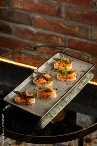 Obraz na płótnie baked bruschetta with salmon, cheese, sun-dried tomatoes and avocado in gray plate on bright background w salonie