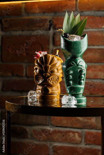 Tiki Drink Cocktails. Two cocktails in different glasses against the background of a bar decorated with dried fruits and tropical leaves.