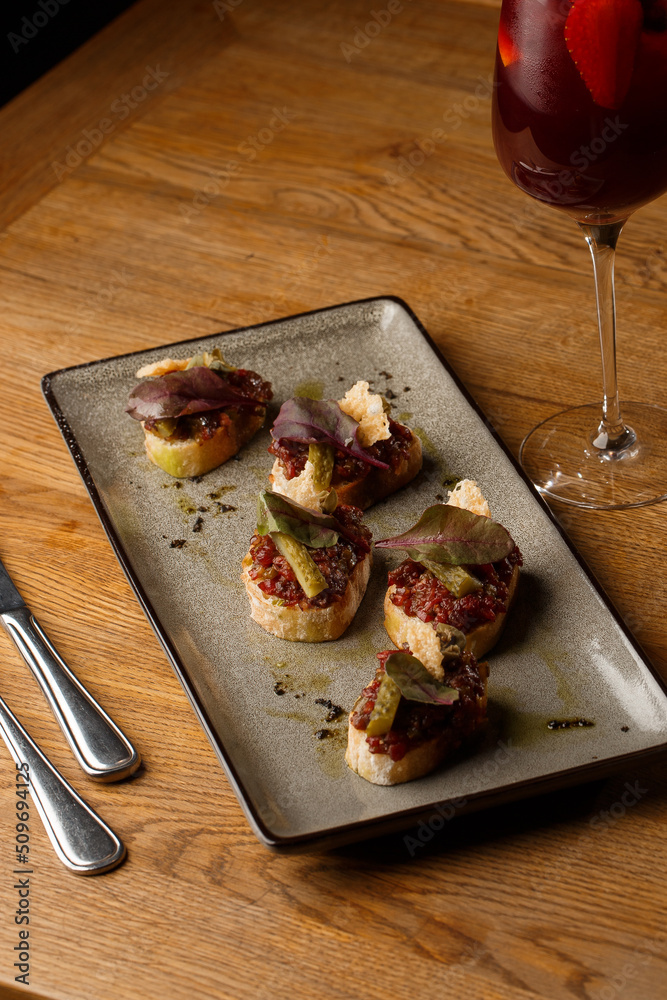 Four bruschettas with beef tartare on a plate, Crostini with Beef Tartare, beef Bruschetta, sandwich with raw gourmet beef.