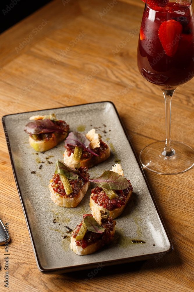 Four bruschettas with beef tartare on a plate, Crostini with Beef Tartare, beef Bruschetta, sandwich with raw gourmet beef.