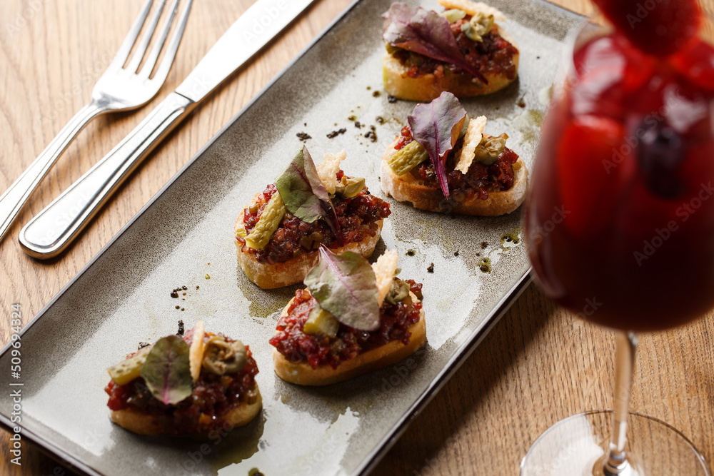 Four bruschettas with beef tartare on a plate, Crostini with Beef Tartare, beef Bruschetta, sandwich with raw gourmet beef.