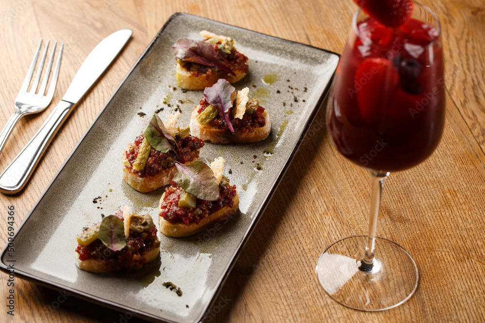 Four bruschettas with beef tartare on a plate, Crostini with Beef Tartare, beef Bruschetta, sandwich with raw gourmet beef.