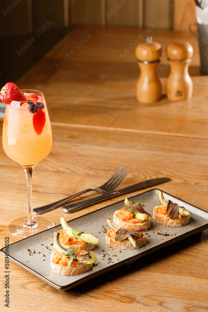baked bruschetta with salmon, cheese, sun-dried tomatoes and avocado in gray plate on bright background