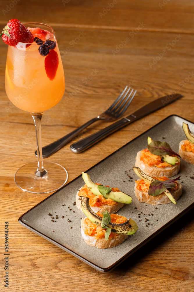 baked bruschetta with salmon, cheese, sun-dried tomatoes and avocado in gray plate on bright background