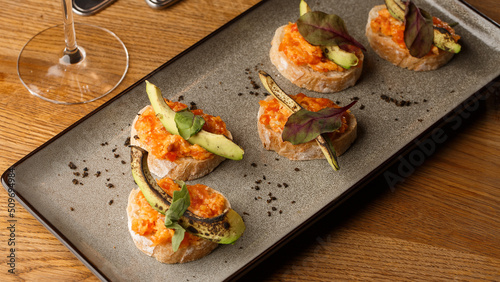 Obraz na płótnie baked bruschetta with salmon, cheese, sun-dried tomatoes and avocado in gray plate on bright background w salonie
