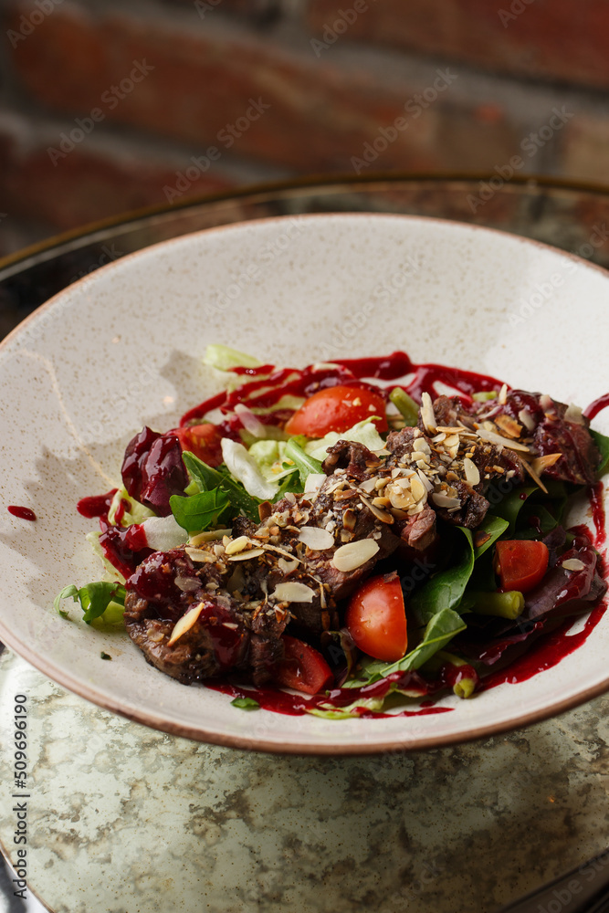 Salad with veal and tomatoes. Beef steak with raw vegetables mix side view. Grilled meat with garnish close-up. Delicious main course on table