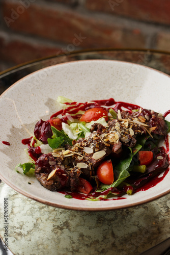 Obraz na płótnie Salad with veal and tomatoes. Beef steak with raw vegetables mix side view. Grilled meat with garnish close-up. Delicious main course on table w salonie
