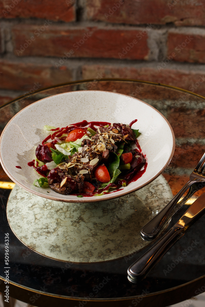 Salad with veal and tomatoes. Beef steak with raw vegetables mix side view. Grilled meat with garnish close-up. Delicious main course on table
