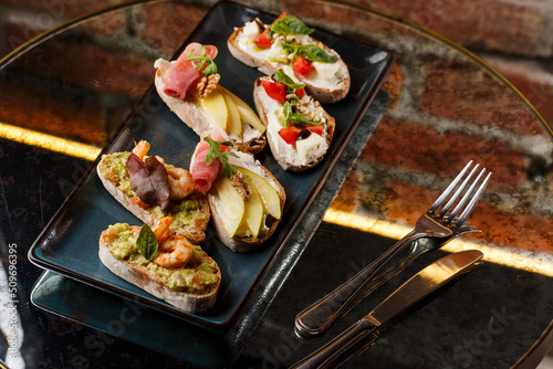 Obraz na płótnie Bruschettas with vegetables. Start dishes with cherry tomatoes, avocado, cream cheese and shrimps. Food composition, tasty italian meal w salonie