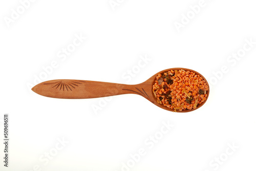 Lentils with spices in wooden spoon on white background, close-up. Ingredients for Indian Masurdal soup. Dry legumes. Long-term storage Healthy Food