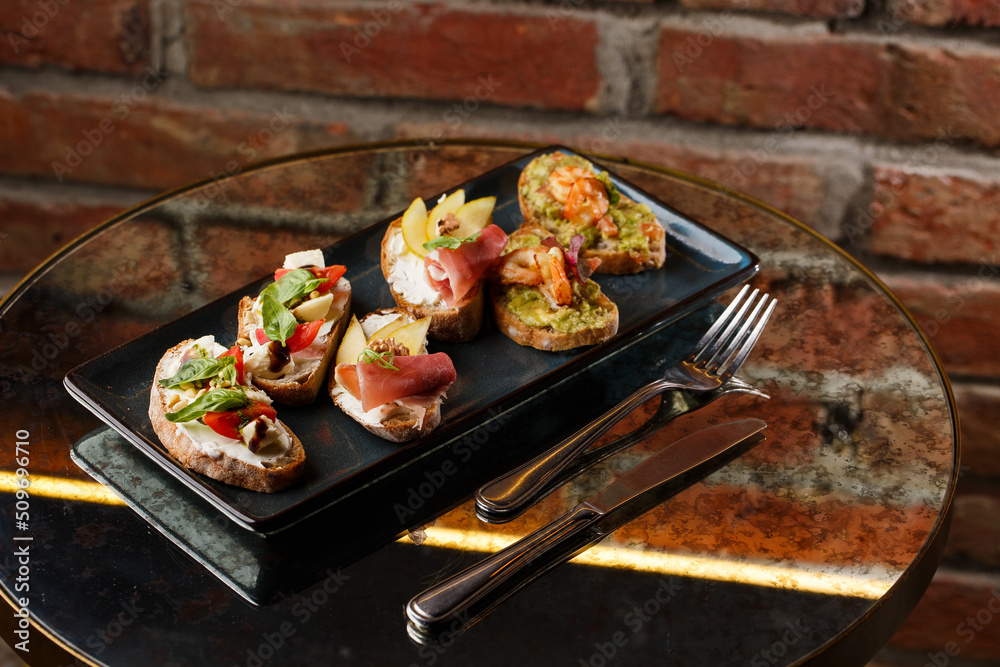 Bruschettas with vegetables. Start dishes with cherry tomatoes, avocado, cream cheese and shrimps. Food composition, tasty italian meal