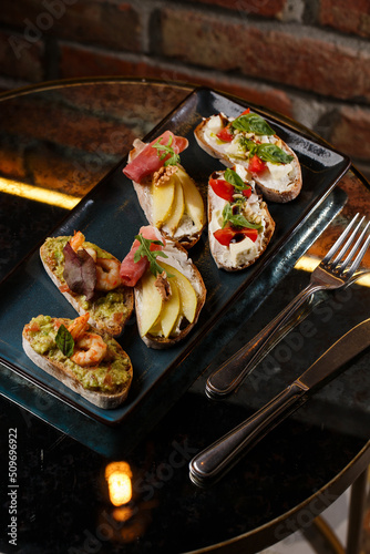 Obraz na płótnie Bruschettas with vegetables. Start dishes with cherry tomatoes, avocado, cream cheese and shrimps. Food composition, tasty italian meal w salonie