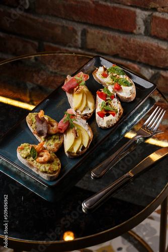 Obraz na płótnie Bruschettas with vegetables. Start dishes with cherry tomatoes, avocado, cream cheese and shrimps. Food composition, tasty italian meal w salonie