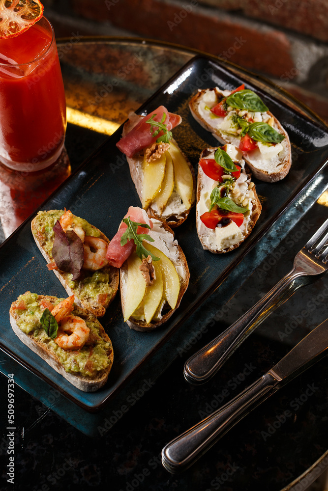 Bruschettas with vegetables. Start dishes with cherry tomatoes, avocado, cream cheese and shrimps. Food composition, tasty italian meal
