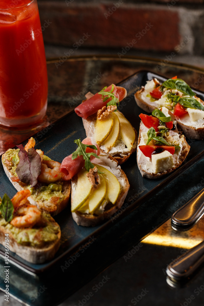 Bruschettas with vegetables. Start dishes with cherry tomatoes, avocado, cream cheese and shrimps. Food composition, tasty italian meal