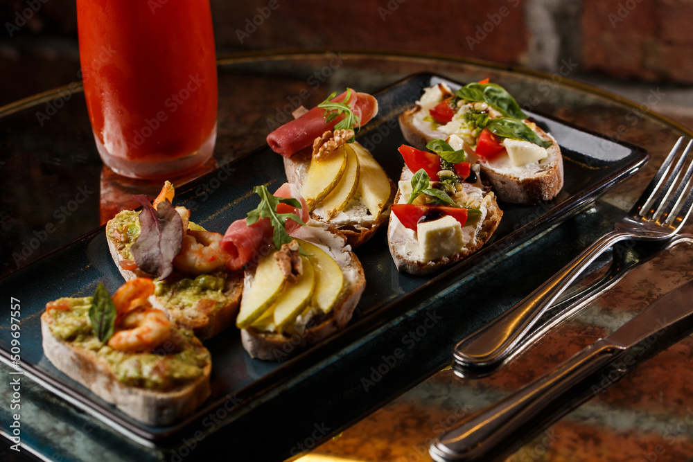 Bruschettas with vegetables. Start dishes with cherry tomatoes, avocado, cream cheese and shrimps. Food composition, tasty italian meal