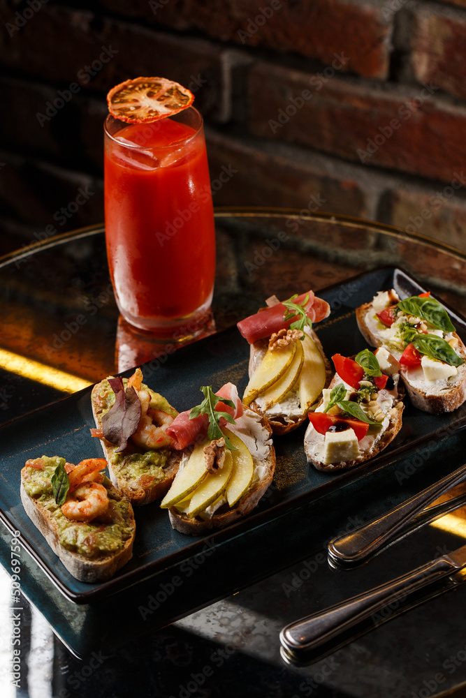 Bruschettas with vegetables. Start dishes with cherry tomatoes, avocado, cream cheese and shrimps. Food composition, tasty italian meal