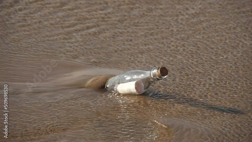 A message in a bottle washed up on the beach by waves photo