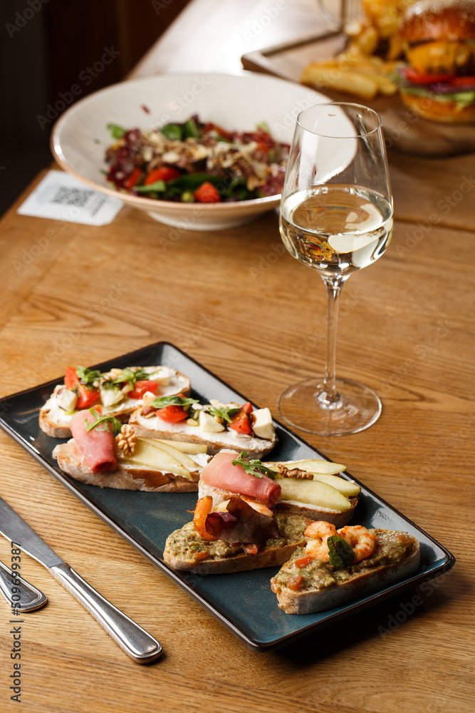Bruschettas with vegetables. Start dishes with cherry tomatoes, avocado, cream cheese and shrimps. Food composition, tasty italian meal