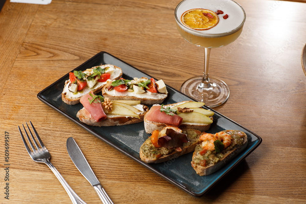 Bruschettas with vegetables. Start dishes with cherry tomatoes, avocado, cream cheese and shrimps. Food composition, tasty italian meal