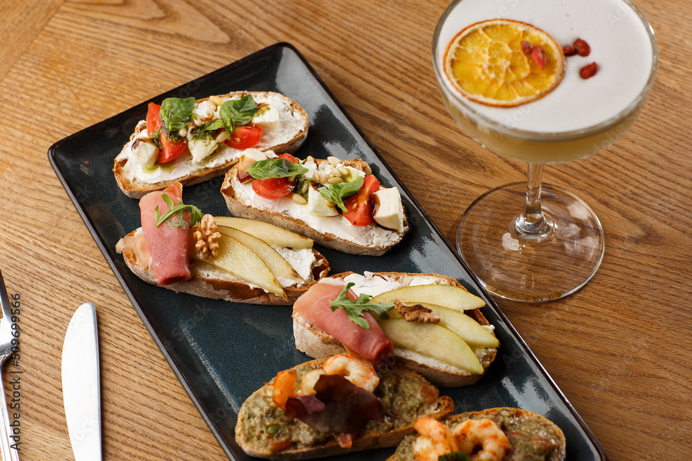 Bruschettas with vegetables. Start dishes with cherry tomatoes, avocado, cream cheese and shrimps. Food composition, tasty italian meal
