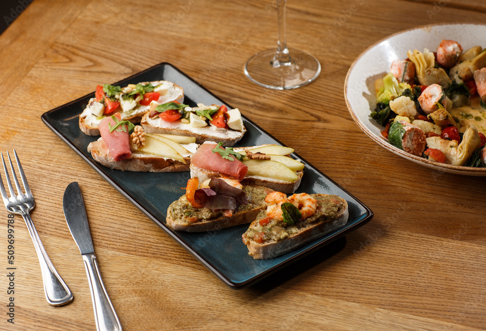 Bruschettas with vegetables. Start dishes with cherry tomatoes, avocado, cream cheese and shrimps. Food composition, tasty italian meal