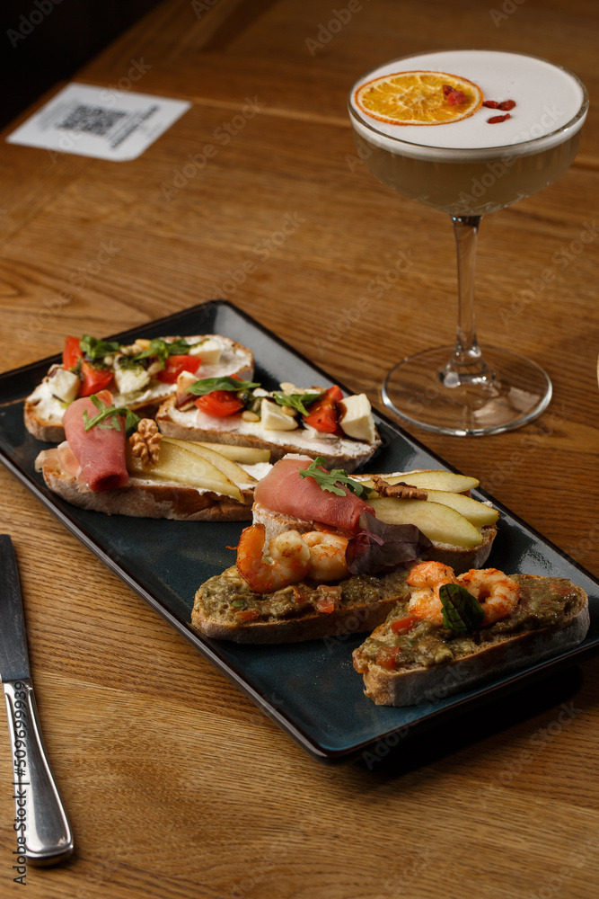 Bruschettas with vegetables. Start dishes with cherry tomatoes, avocado, cream cheese and shrimps. Food composition, tasty italian meal
