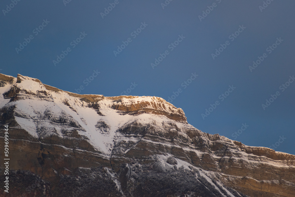 cerro rocoso cubierto de nueve blanca con cielos azules oscuros de atardecer 