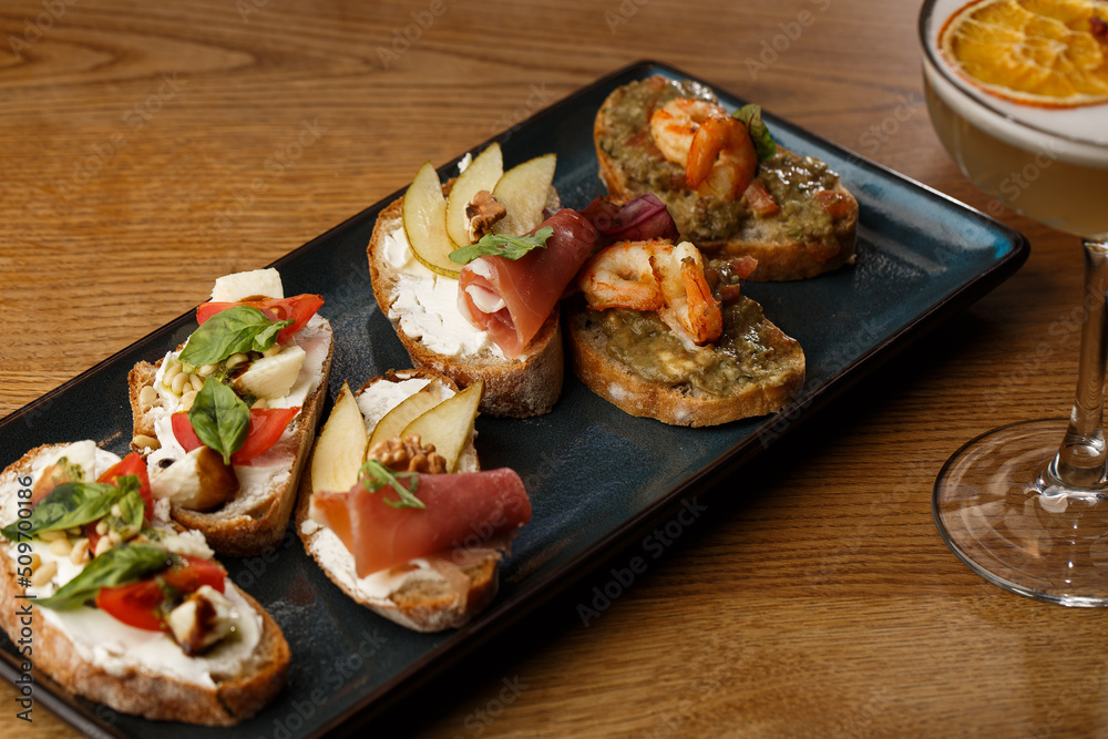 Bruschettas with vegetables. Start dishes with cherry tomatoes, avocado, cream cheese and shrimps. Food composition, tasty italian meal
