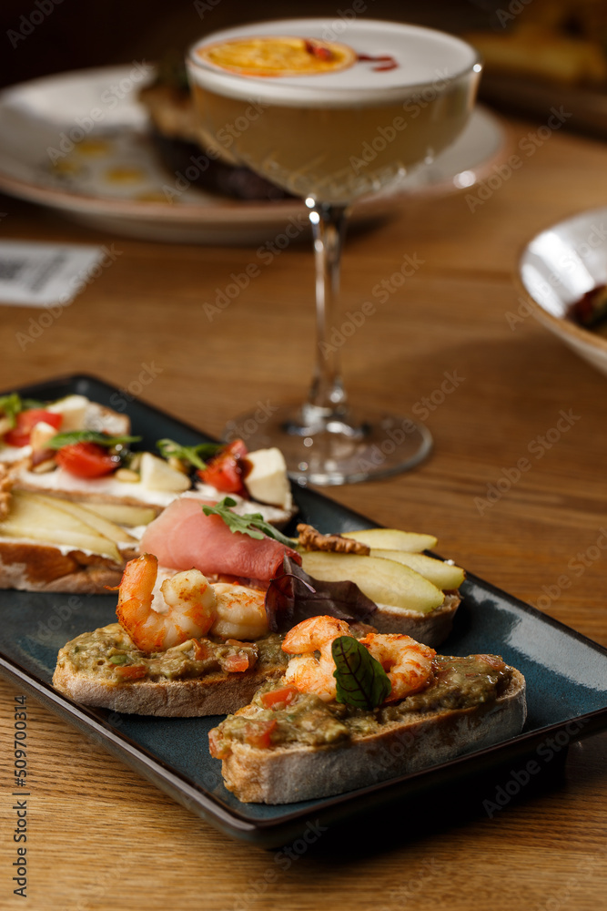 Bruschettas with vegetables. Start dishes with cherry tomatoes, avocado, cream cheese and shrimps. Food composition, tasty italian meal