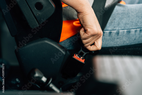 Close up of woman hand buckle the car safety belt. Truck driver occupation 