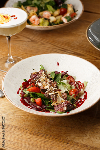 Obraz na płótnie Salad with veal and tomatoes. Beef steak with raw vegetables mix side view. Grilled meat with garnish close-up. Delicious main course on table w salonie