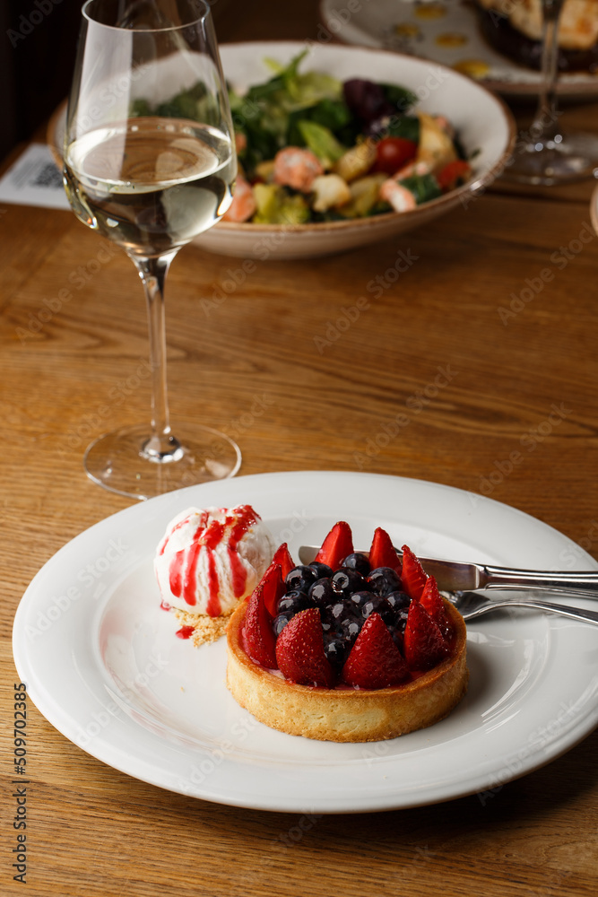 Berry tartlets with curd cream on a wooden background. Summer fruit baking. Tartlets with raspberries, blueberries and red currants. Served with ice cream.