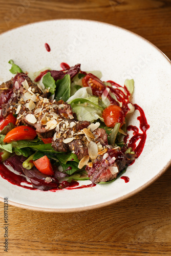Obraz na płótnie Salad with veal and tomatoes. Beef steak with raw vegetables mix side view. Grilled meat with garnish close-up. Delicious main course on table w salonie