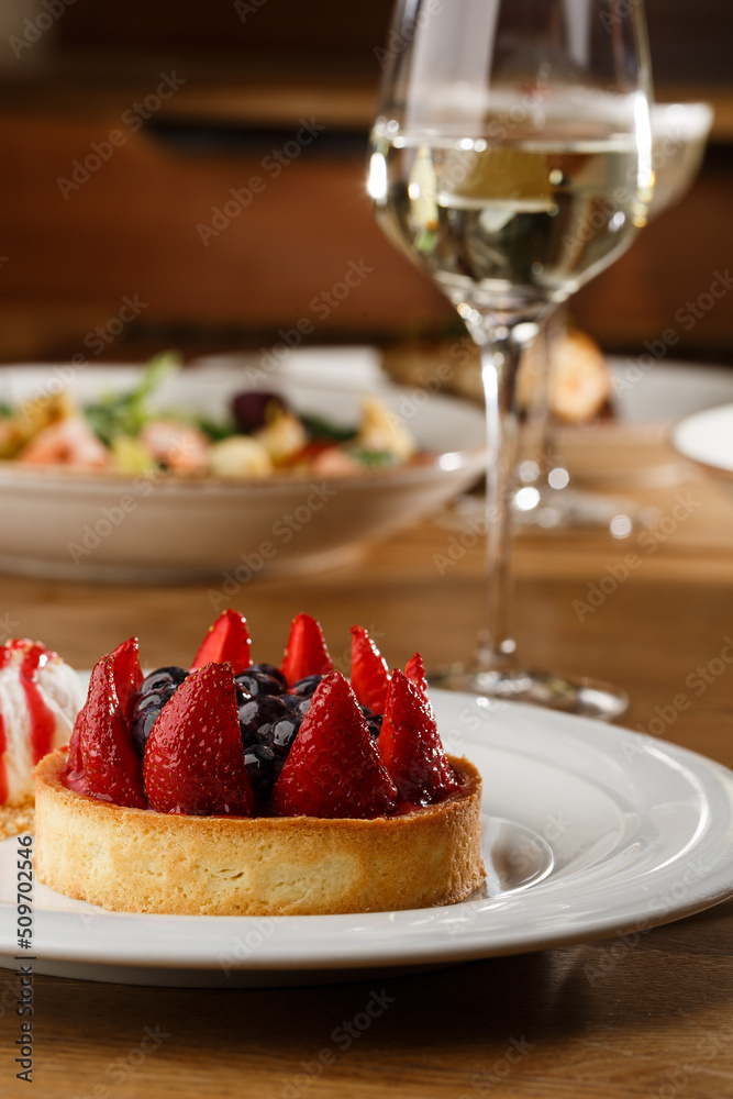 Berry tartlets with curd cream on a wooden background. Summer fruit baking. Tartlets with raspberries, blueberries and red currants. Served with ice cream.