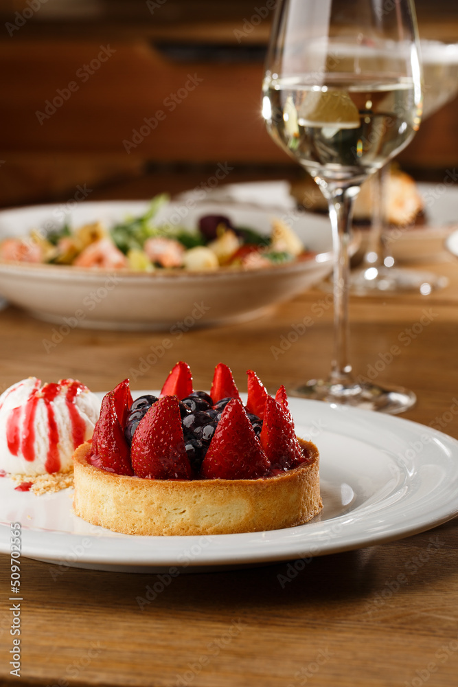 Berry tartlets with curd cream on a wooden background. Summer fruit baking. Tartlets with raspberries, blueberries and red currants. Served with ice cream.