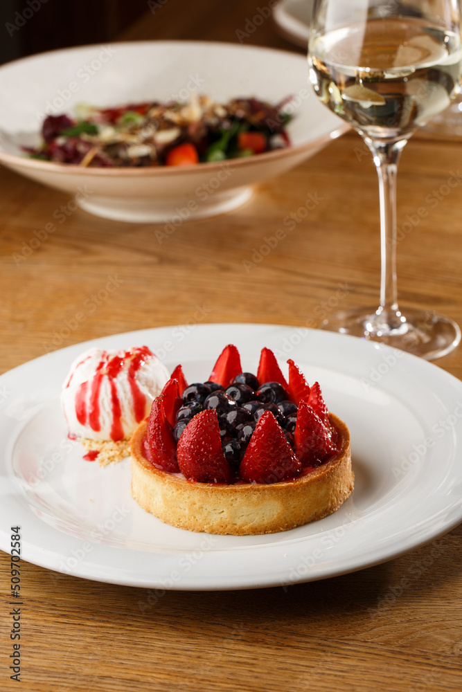 Berry tartlets with curd cream on a wooden background. Summer fruit baking. Tartlets with raspberries, blueberries and red currants. Served with ice cream.